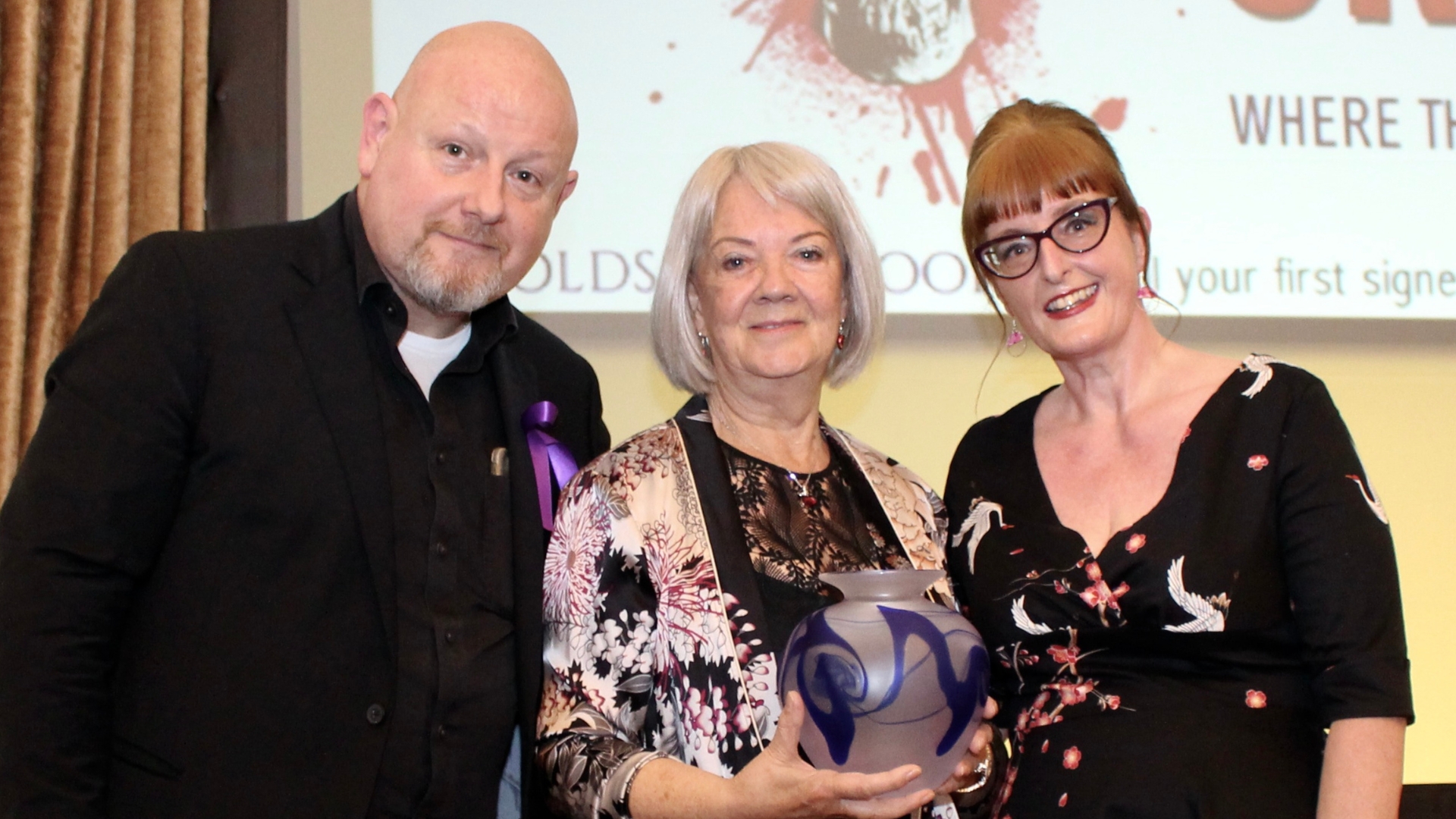 CrimeFest organisers Adrian Muller and Donna Moore with (centre) title sponsor, Specsaver's founder Dame Mary Perkins